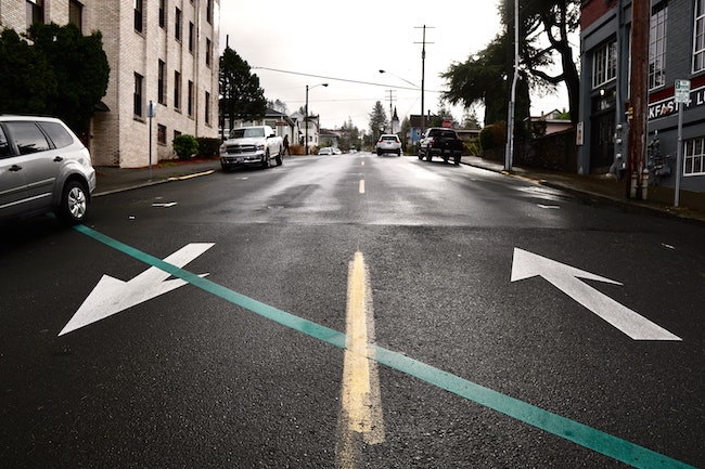 Photo of a two way street with arrows pointing in each direction.