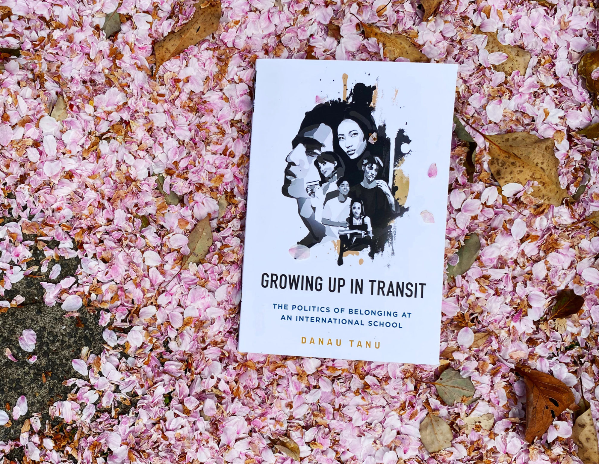Photo of Growing Up in Transit book on a bed of pink sakura petals