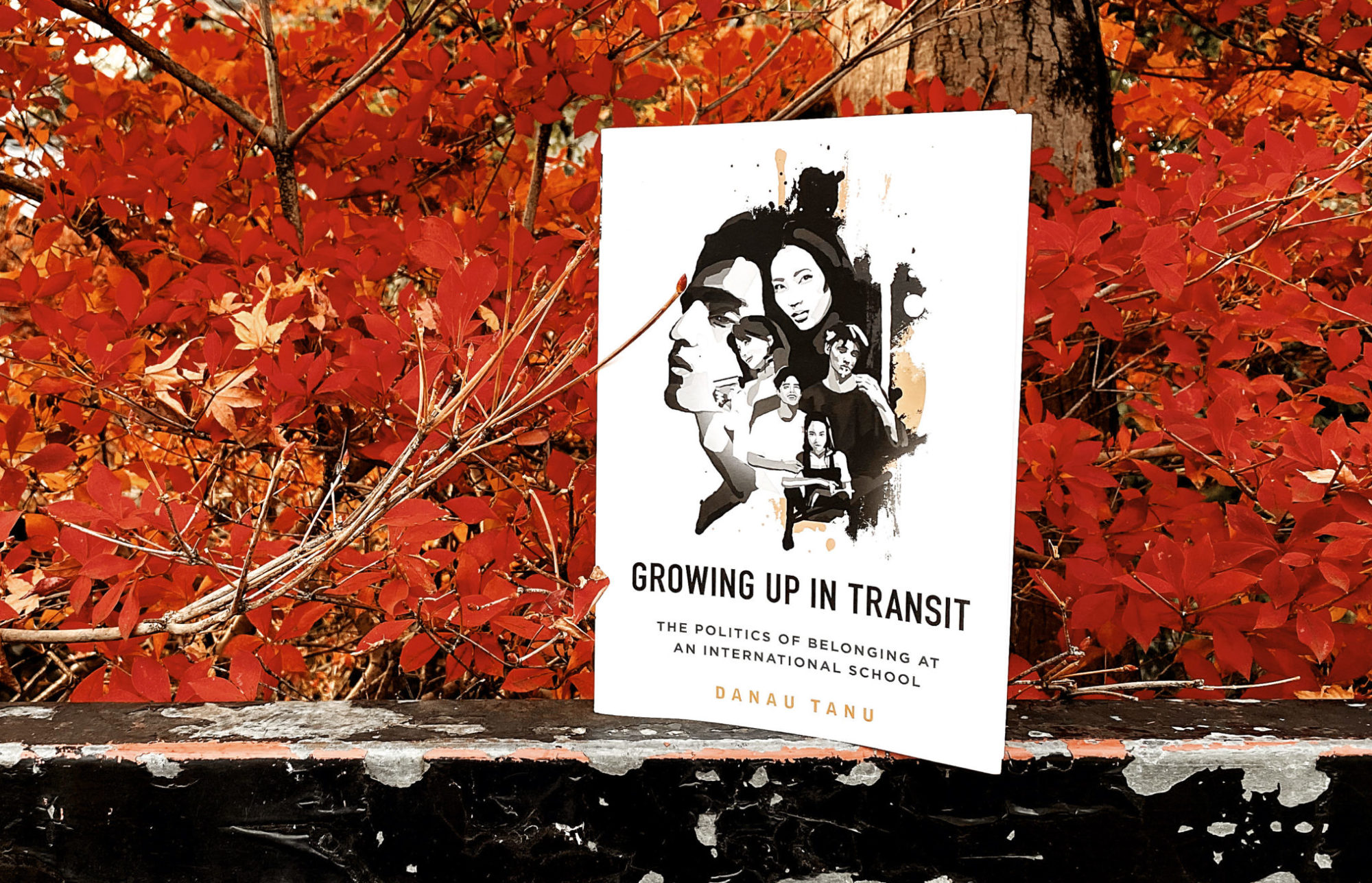 Photo of Growing Up in Transit book with Kyoto's red autumn leaves in the background