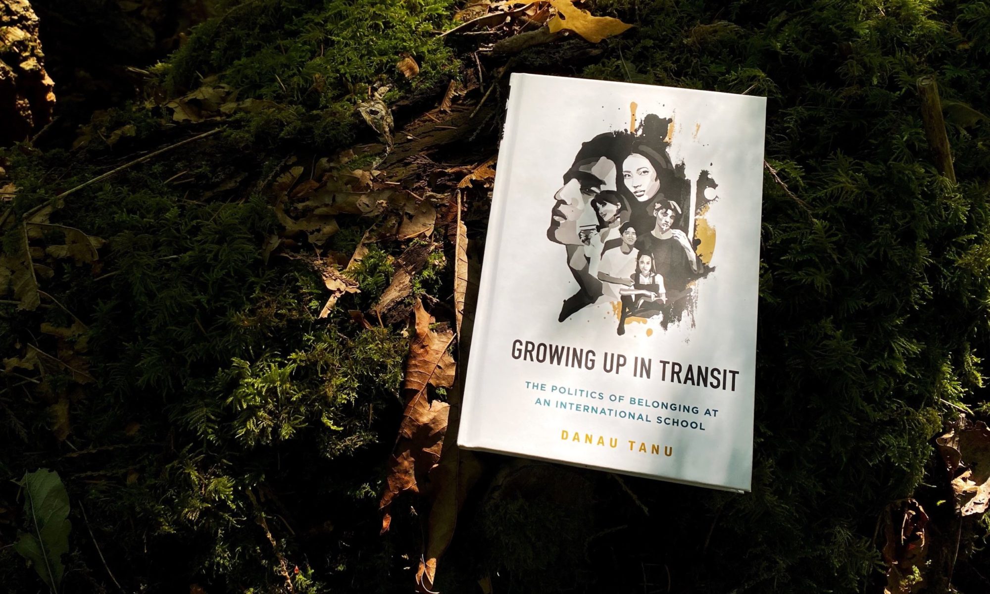 Growing Up in Transit book on a log covered by moss and leaves